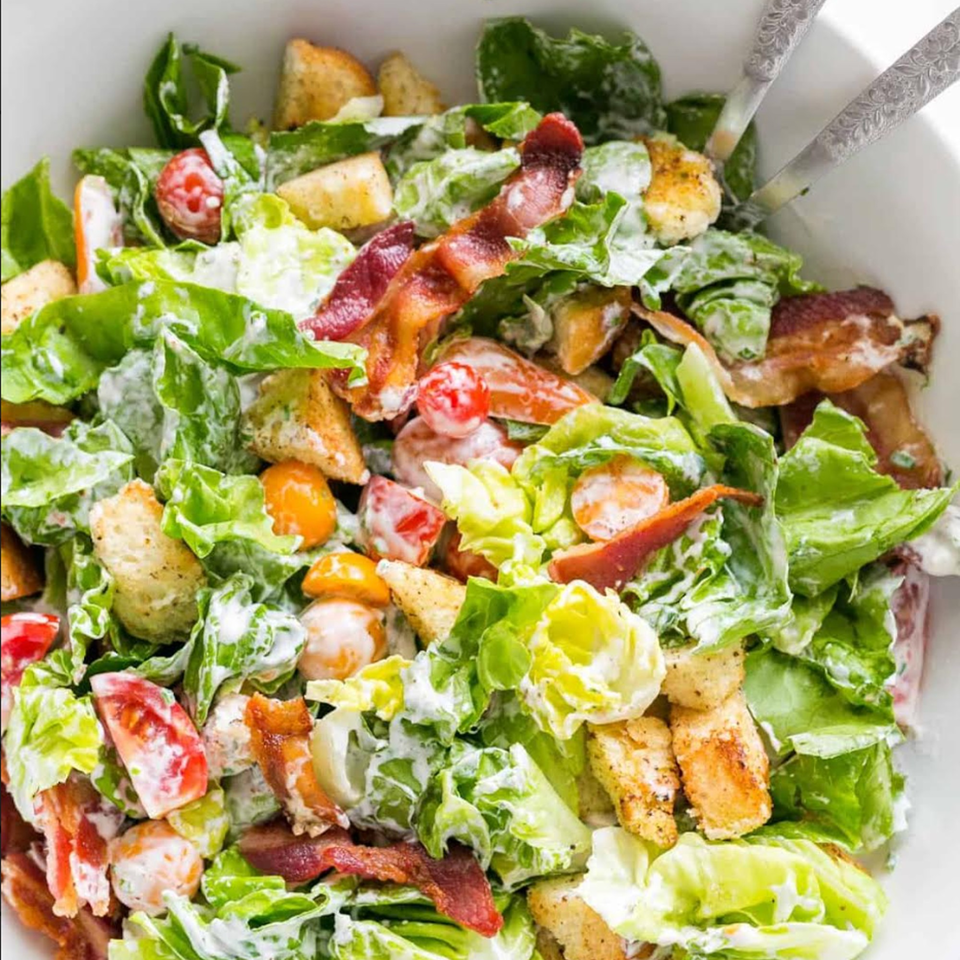 A fresh Caesar salad with crisp lettuce, cherry tomatoes, bacon, croutons, and creamy dressing.