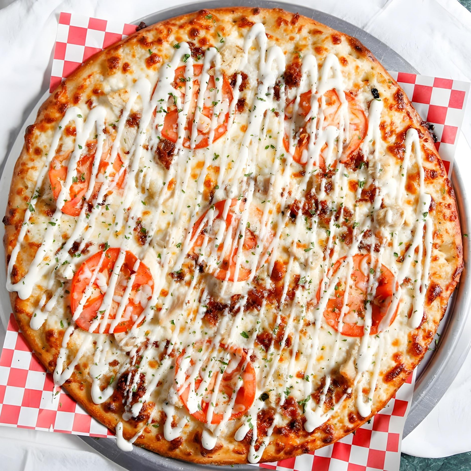 Bloom pizzeria's chicken bacon ranch pizza, topped with tomatoes and parsley, on a checkered paper.