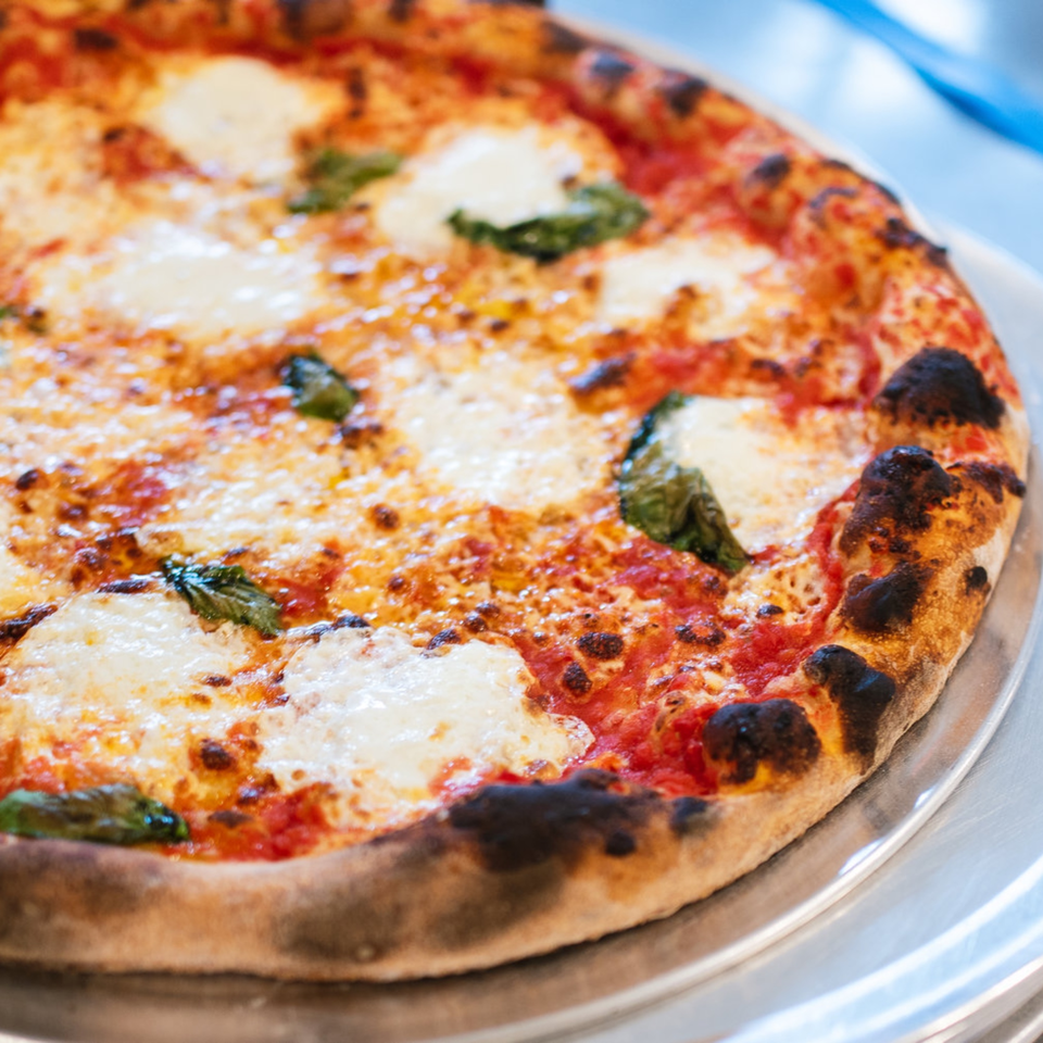 A freshly baked Bloom pizzeria Margherita pizza with melted mozzarella, red sauce, and basil.