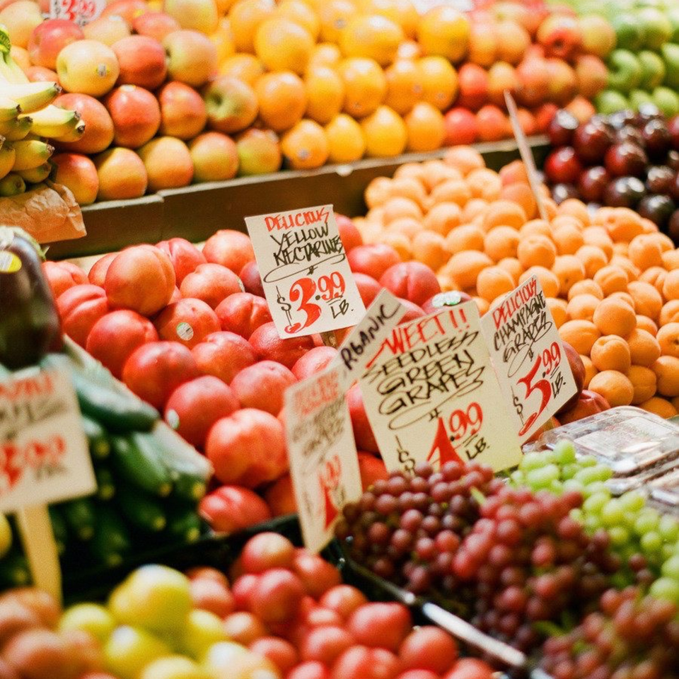 A vibrant display of fresh produce, including apples, nectarines, grapes, and other fruits with price tags.